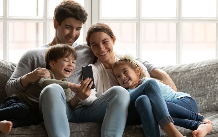 image: family with two adorable small kids looking at phone screen