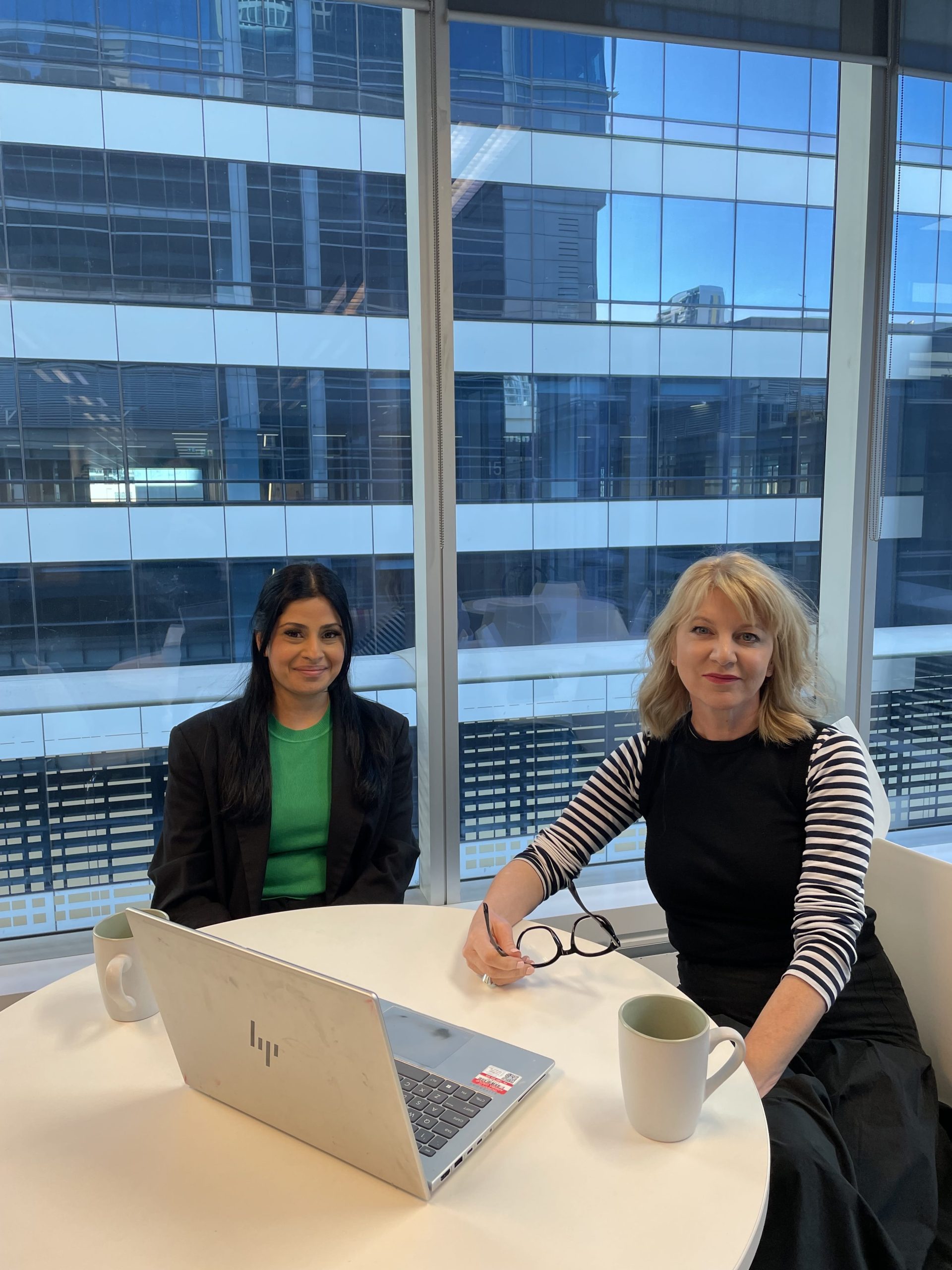 Two Arriba Group team members sitting at a table with a laptop in a modern office setting
