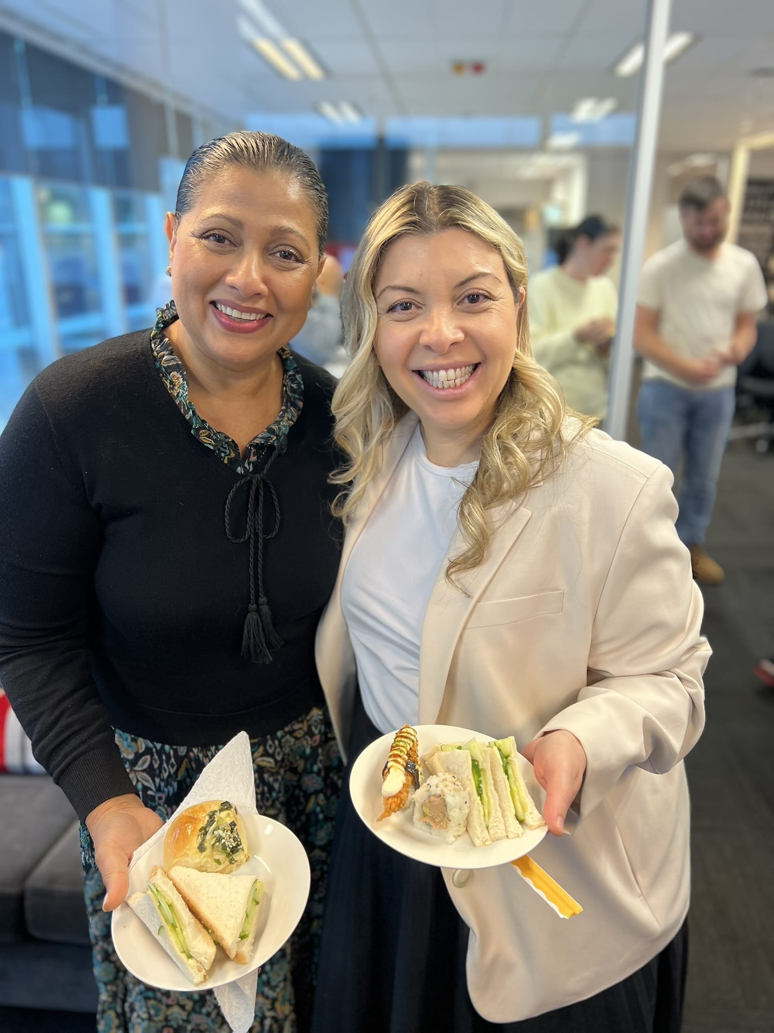 Arriba Group colleagues smiling while holding plates of food at a workplace gathering