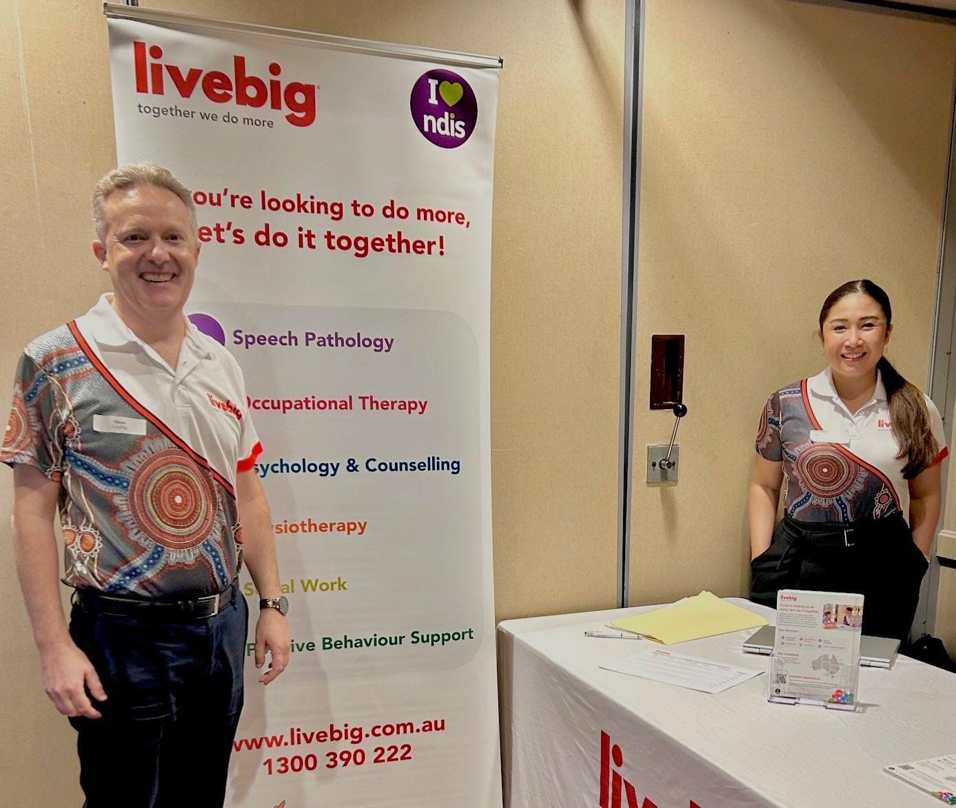 Two LiveBig team members standing at an exhibition booth with a LiveBig banner display
